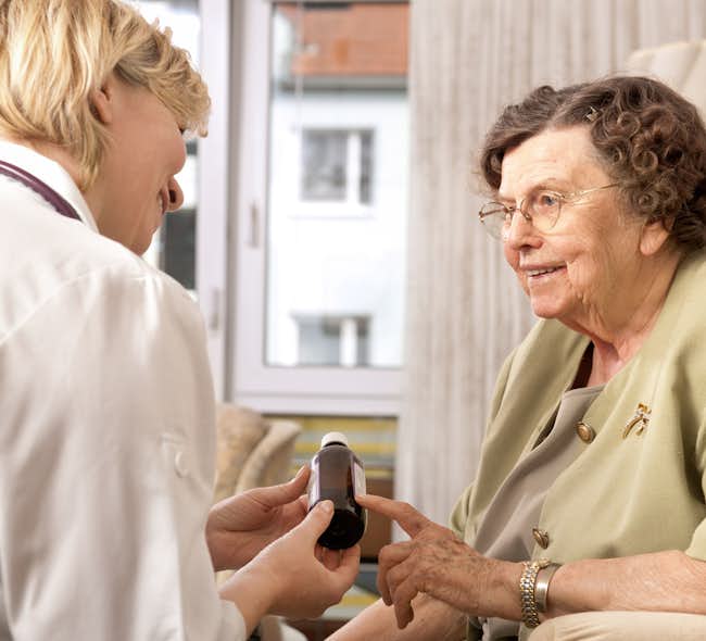 An elderly woman smiles at her pharmacist.
